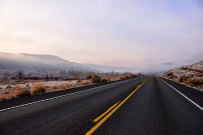 Empty road by mountain against sky