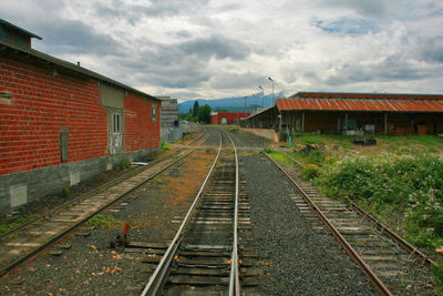 Railroad tracks by buildings against sky