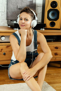 Portrait of woman listening music at home