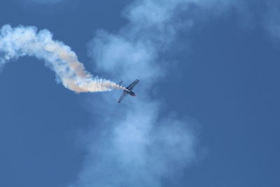 Low angle view of fighter plane flying against blue sky