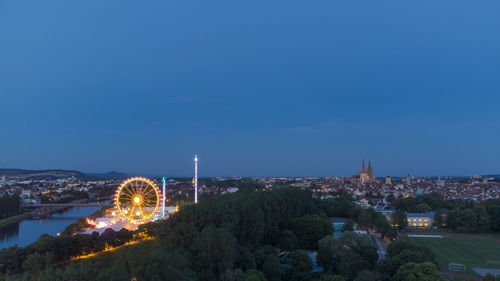 Illuminated cityscape against clear blue sky