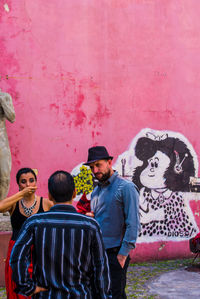 People standing against graffiti wall