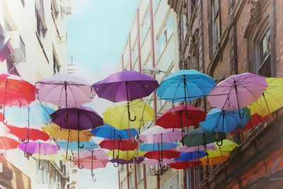 Low angle view of umbrellas hanging amidst buildings