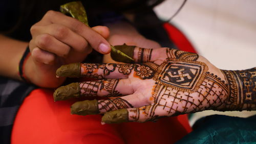 Woman making henna tattoo on hand of bride