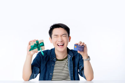 Portrait of smiling man holding camera over white background