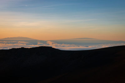 Peak of mauna kea, big island seen from haleakala on maui, hawaii, usa at sunrise against sky