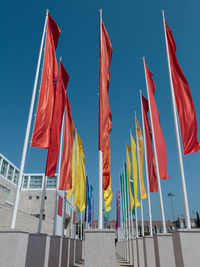 Low angle view of flags against clear blue sky