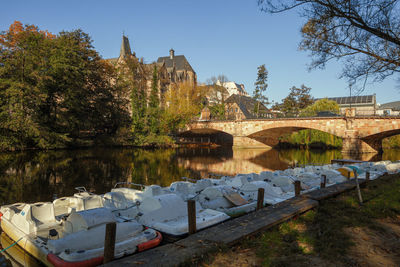 Bridge over river by buildings against clear sky