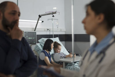 Side view of man using mobile phone while sitting at clinic