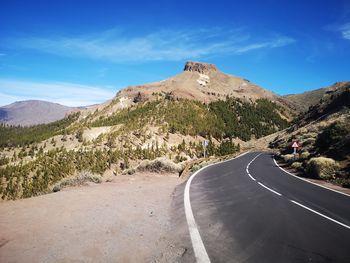 Road leading towards mountains against sky