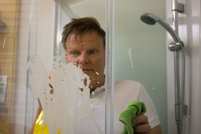 Mature man cleaning bathroom glass