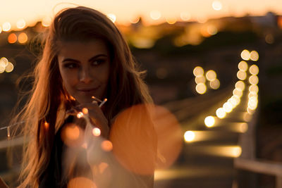 Close-up portrait of young woman in illuminated city