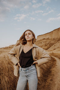 Young woman standing by plants against sky