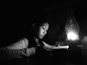 Portrait of young woman reading book in darkroom