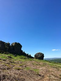 Rock formations on landscape against clear blue sky