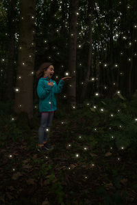 Full length of woman standing on illuminated tree at night