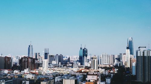 Buildings in city against clear blue sky