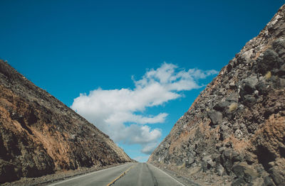 Road amidst mountains against blue sky