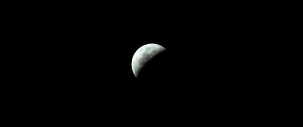 Low angle view of half moon against black background