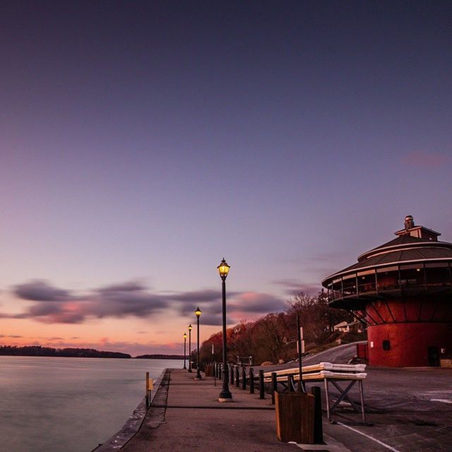 built structure, architecture, street light, sky, building exterior, the way forward, sea, lighting equipment, railing, illuminated, sunset, lamp post, dusk, water, empty, outdoors, copy space, walkway, incidental people, horizon over water