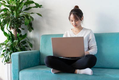 Young woman using laptop while sitting on table