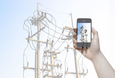 Close-up of hand holding smart phone against clear sky