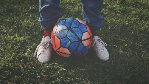 Low section of man with soccer ball on grassy field