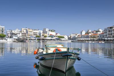 Boats moored in river against clear blue sky