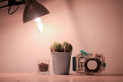 Close-up of illuminated light bulb on table against wall at home