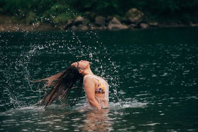 Side view of woman tossing hair in sea