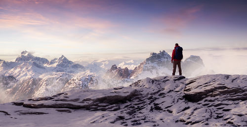 Rear view of man standing on snowcapped mountain