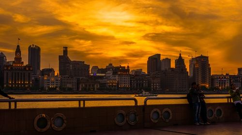 Cityscape by river during sunset