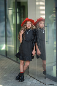 Portrait of a smiling young woman standing against glass wall