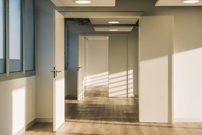 Interior of empty spacious loft hallway with geometrical shadows and sunlight on white walls