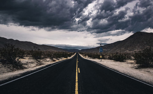 Surface level of empty road against cloudy sky