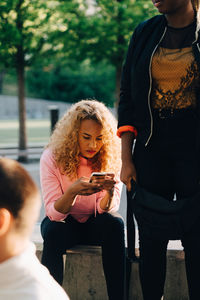 Young woman with friends using smart phone at park