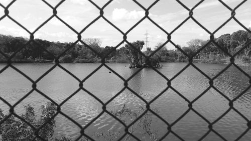 Scenic view of lake seen through chainlink fence