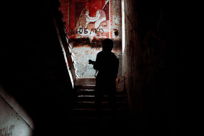 Rear view of silhouette man standing on staircase in building