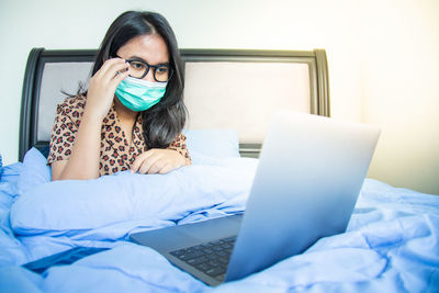 Young woman using mobile phone on bed