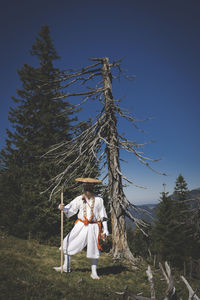 Rear view of woman with arms outstretched against trees