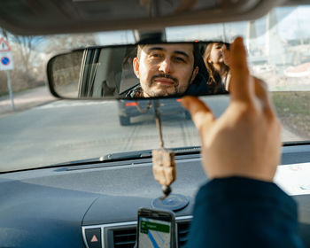 Man looking to daughter through car mirror 