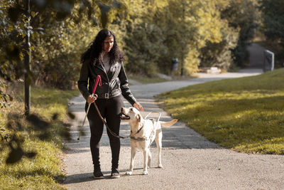 Visually impaired woman standing in park with guide dog