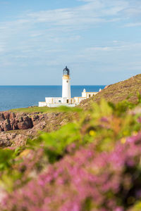 Lighthouse by sea against sky