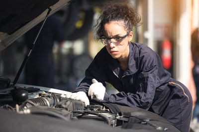 Mechanic repairing the motor or electric parts of a car in a garage