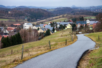 Scenic view of road by houses and trees against mountains