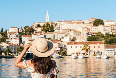 Young woman in white dress in front of old town by sea, summer, travel, vacation, lifestyle.