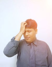 Portrait of young man standing against white background