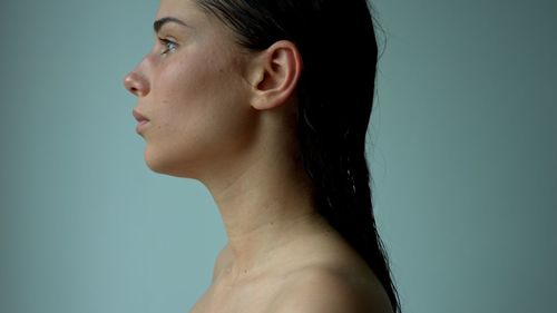 Portrait of young woman against blue background