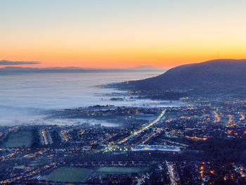 High angle view of townscape by sea against sky during sunset