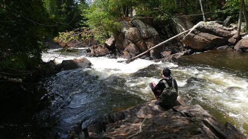 Man sitting on rock in river